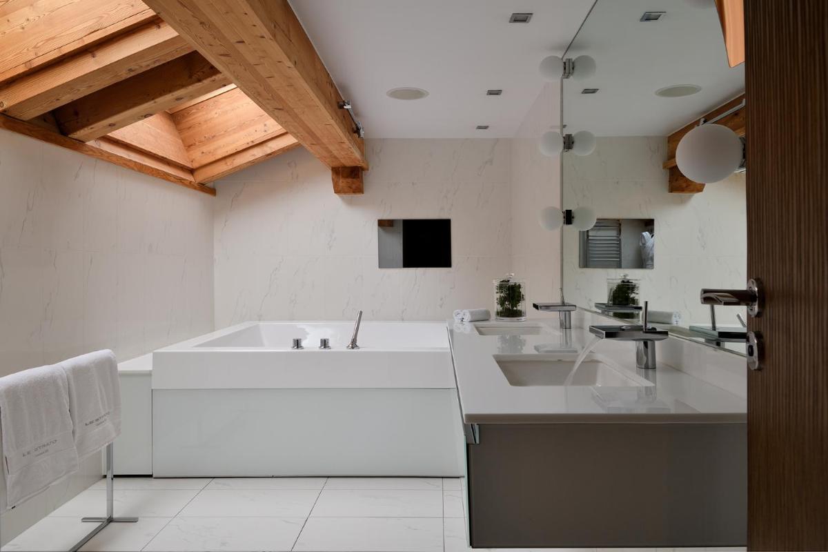 une salle de bain blanche avec une baignoire et un lavabo dans l'établissement Le Strato, à Courchevel une salle de bain blanche avec une baignoire et un lavabo dans l'établissement Le Strato, à Courchevel