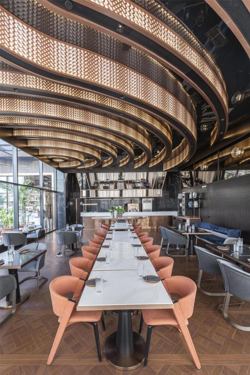 a dining room with tables and chairs and a large chandelier at Radisson Blu Hotel Pune Kharadi in Pune