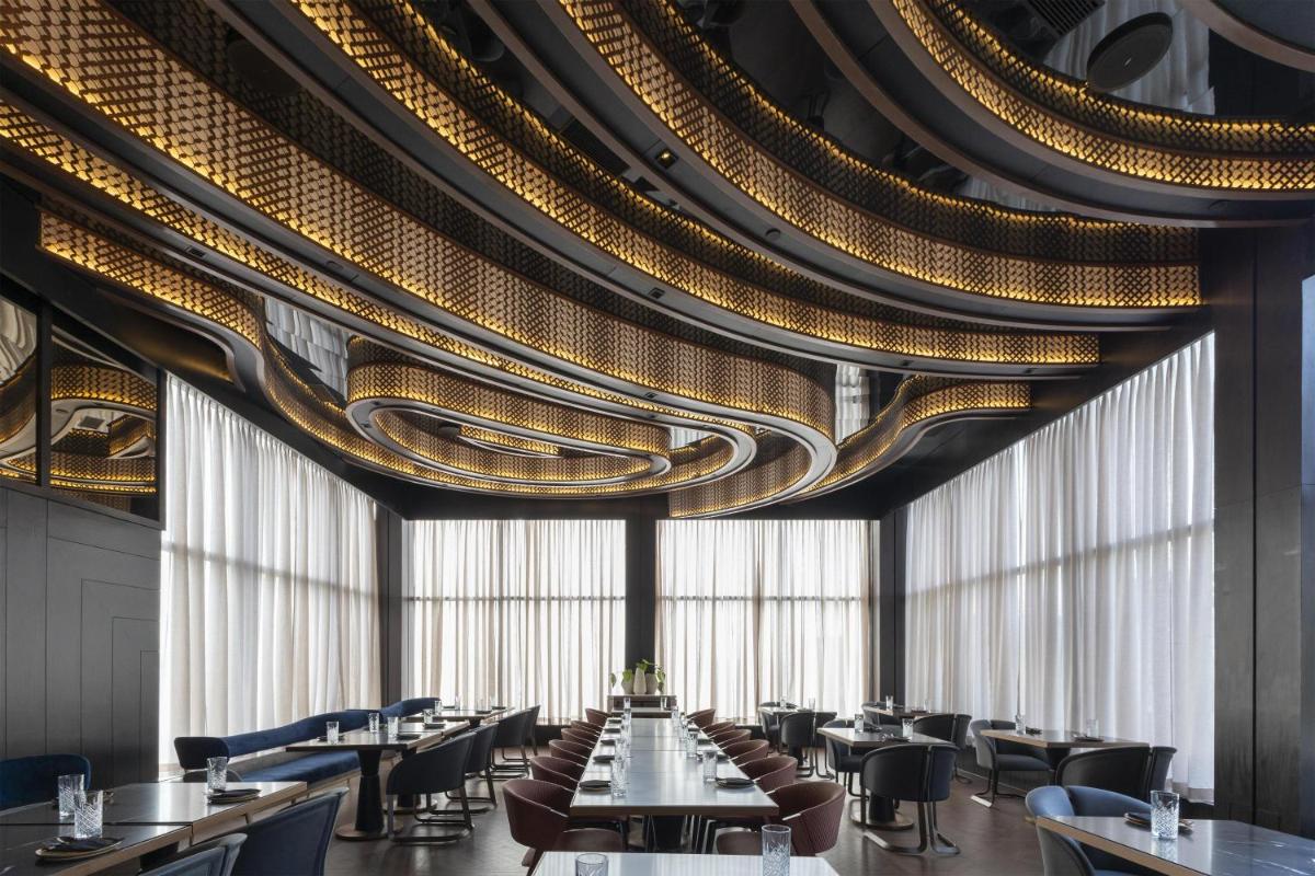 a dining room with tables and chairs and a ceiling at Radisson Blu Hotel Pune Kharadi in Pune