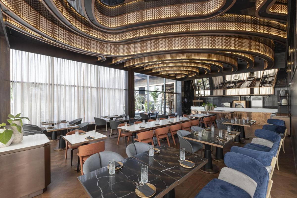 a restaurant with tables and chairs and a ceiling at Radisson Blu Hotel Pune Kharadi in Pune