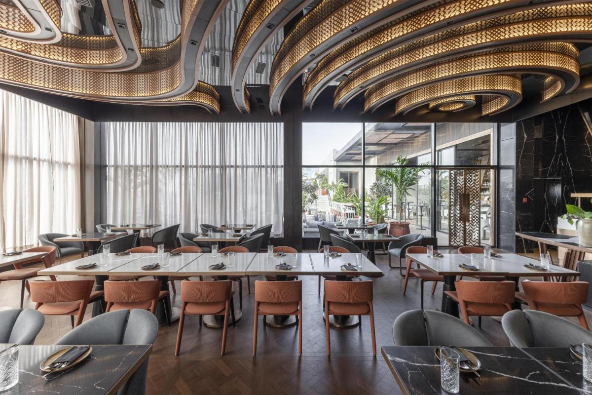 a restaurant with tables and chairs and a ceiling at Radisson Blu Hotel Pune Kharadi in Pune