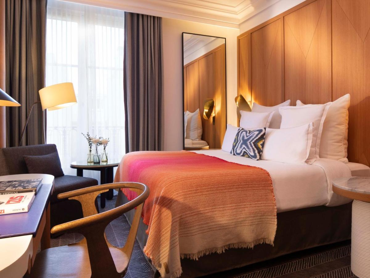 une chambre d'hôtel avec un grand lit et un bureau dans l'établissement Hôtel Vernet Champs Elysées Paris, à Paris