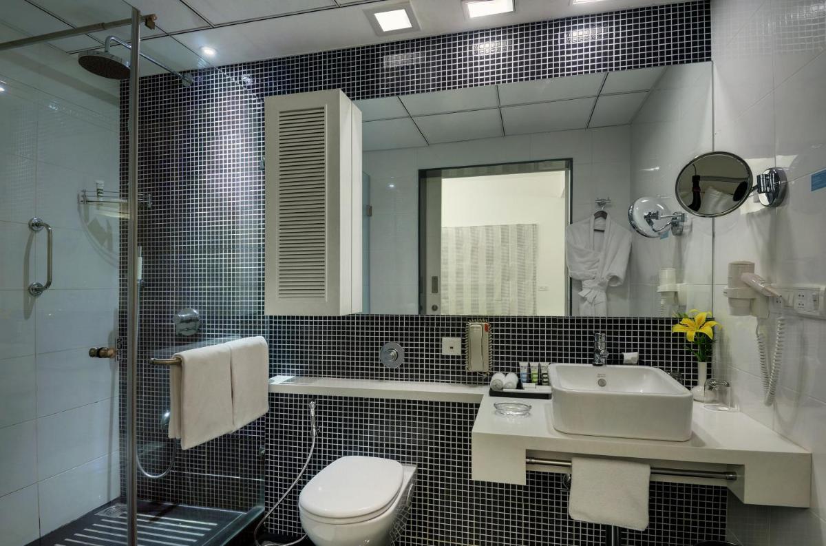 a bathroom with a sink and a toilet and a mirror at Grand Mercure Bangalore - An Accor Brand in Bengaluru