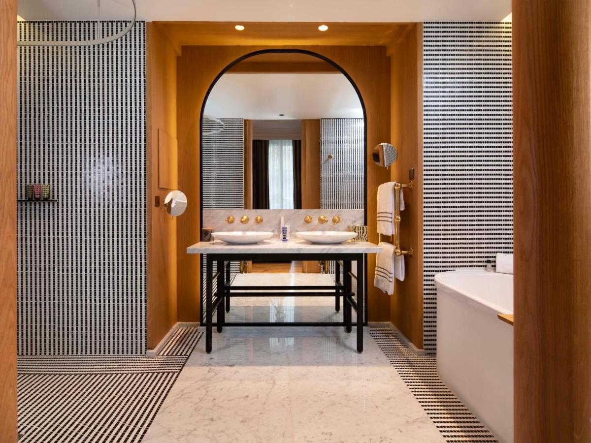 une salle de bain avec deux lavabos, une baignoire et un miroir dans l'établissement Hôtel Vernet Champs Elysées Paris, à Paris 48 autres photos