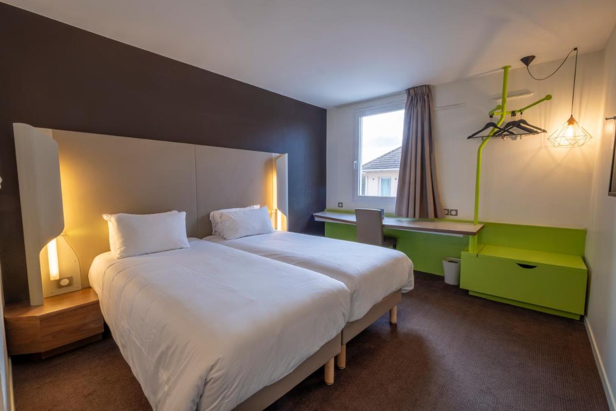 une chambre avec un grand lit et un bureau dans l'établissement Campanile Roissy - Aéroport CDG - Le Mesnil Amelot, au Mesnil-Amelot