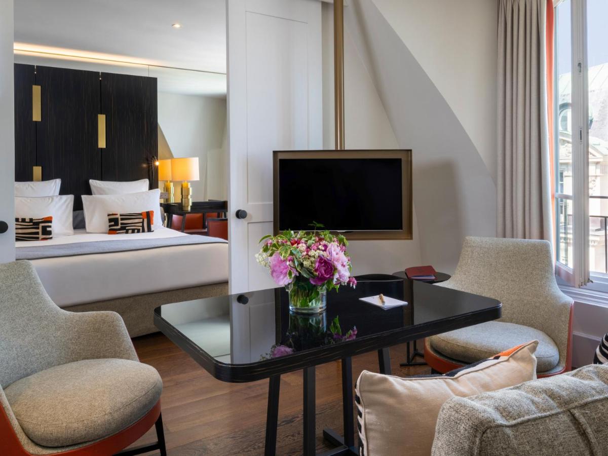un salon avec un lit et une table avec des fleurs dans l'établissement Hotel Montalembert, à Paris