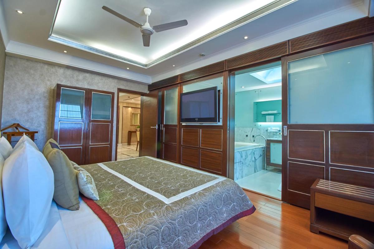 a bedroom with a bed and a tv and a tub at Jaypee Vasant Continental in New Delhi