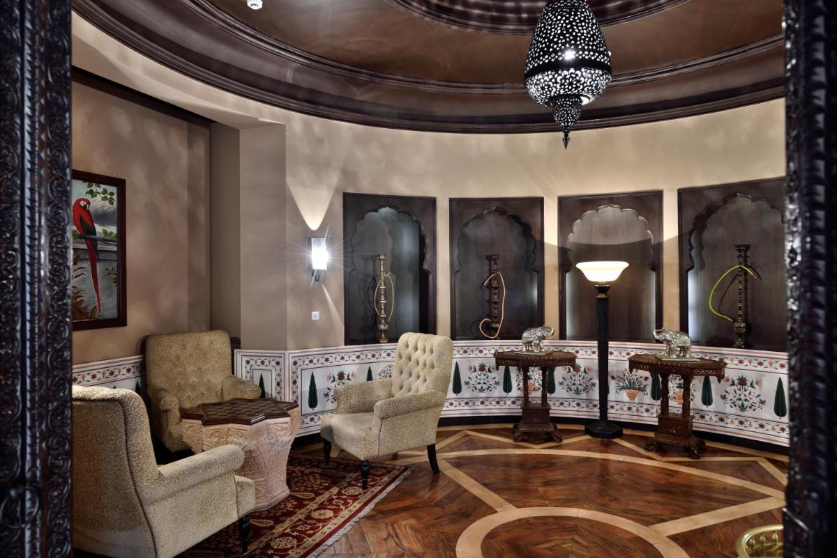 a living room with two chairs and a chandelier at Fairmont Jaipur in Jaipur
