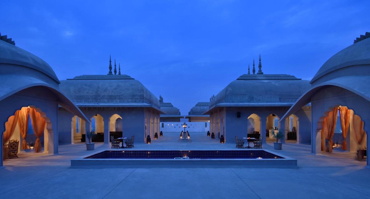 a building with a pool in a courtyard at night at Fairmont Jaipur in Jaipur