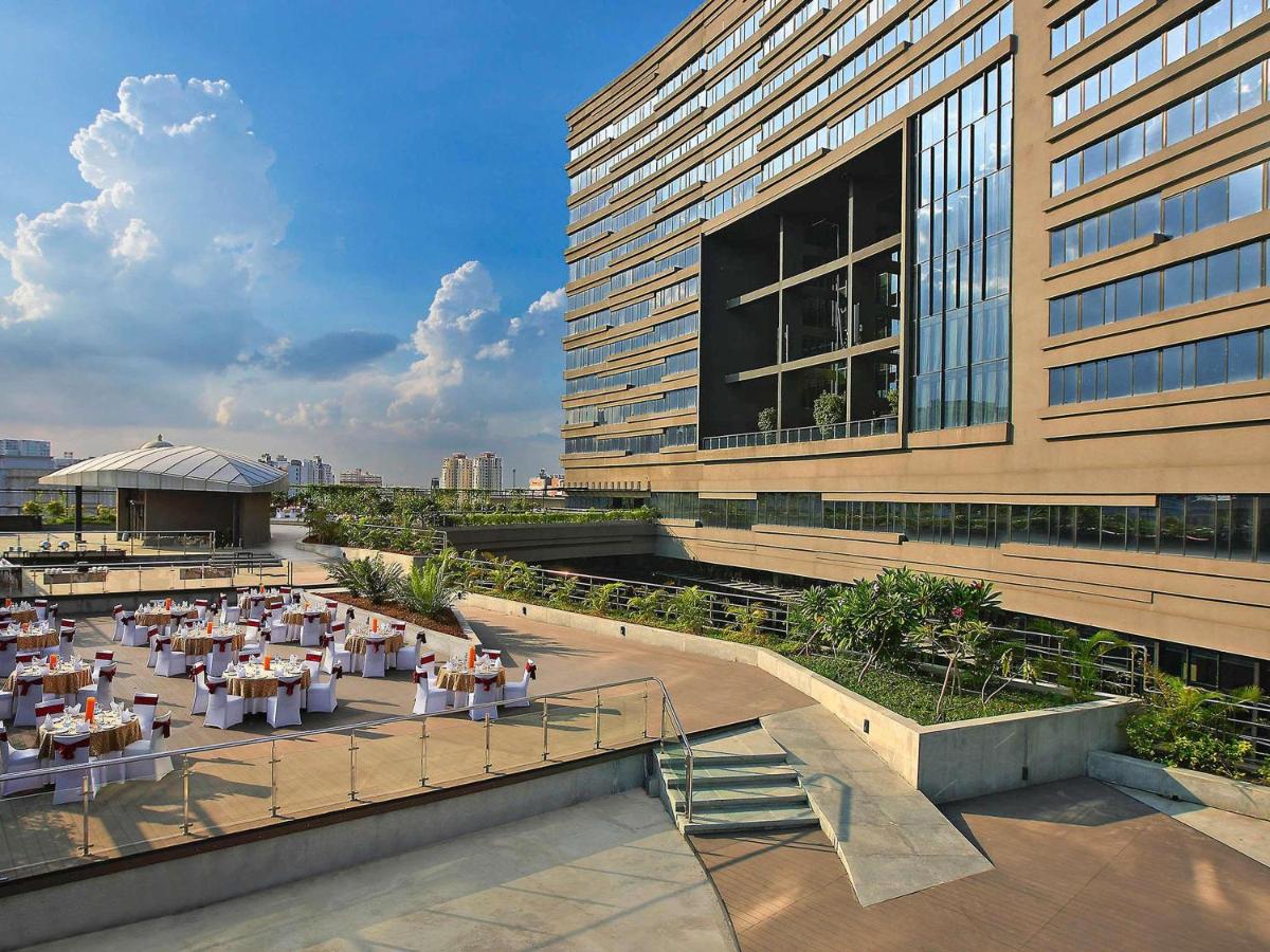 Un restaurante con mesas frente a un edificio. en Novotel Kolkata Hotel and Residences, en Calcuta