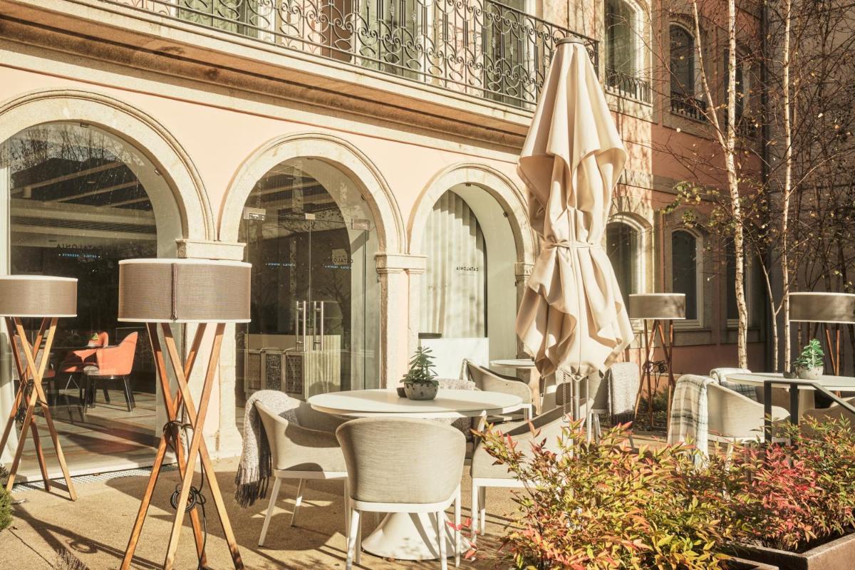 um pátio com mesa, cadeiras e um guarda-sol em Catalonia Porto no Porto