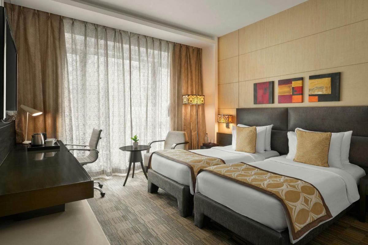 a hotel room with two beds and a desk at Meluha The Fern Mumbai, Powai, Series by Marriott in Mumbai