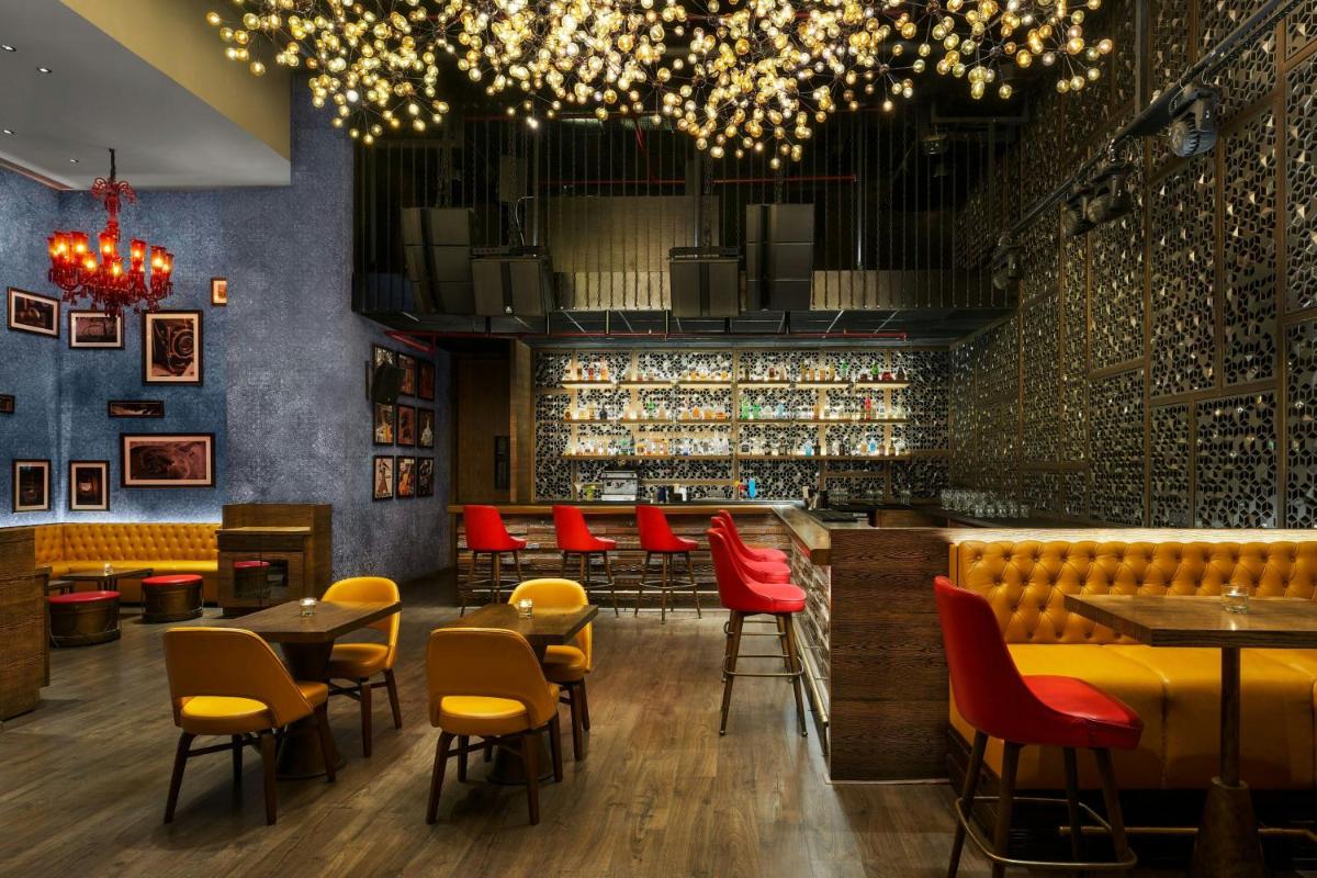 a restaurant with red chairs and tables and a bar at Meluha The Fern Mumbai, Powai, Series by Marriott in Mumbai