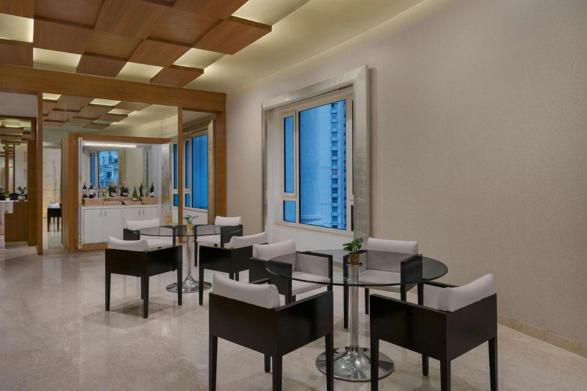 a dining room with tables and chairs and windows at Meluha The Fern Mumbai, Powai, Series by Marriott in Mumbai