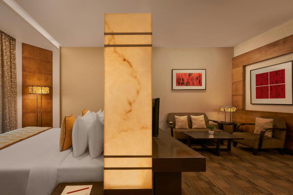 a hotel room with a bed and a living room at Meluha The Fern Mumbai, Powai, Series by Marriott in Mumbai