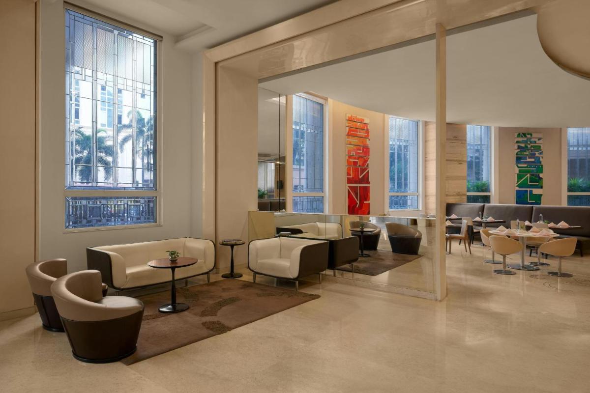 a restaurant with tables and chairs and a large mirror at Meluha The Fern Mumbai, Powai, Series by Marriott in Mumbai