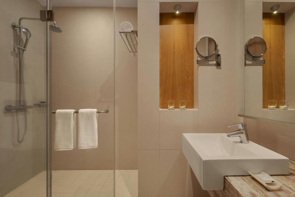 a bathroom with a sink and a glass shower at Meluha The Fern Mumbai, Powai, Series by Marriott in Mumbai