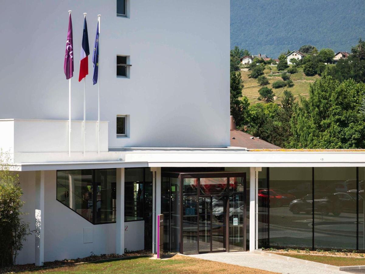 un bâtiment avec deux drapeaux devant dans l'établissement Mercure Aix-les-Bains Domaine de Marlioz Hôtel & Spa, à Aix-les-Bains