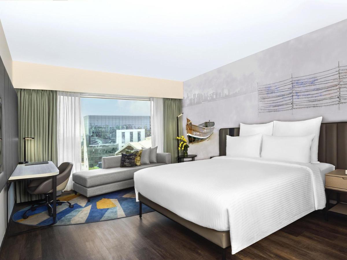 a bedroom with a large bed and a living room at Novotel Mumbai International Airport in Mumbai