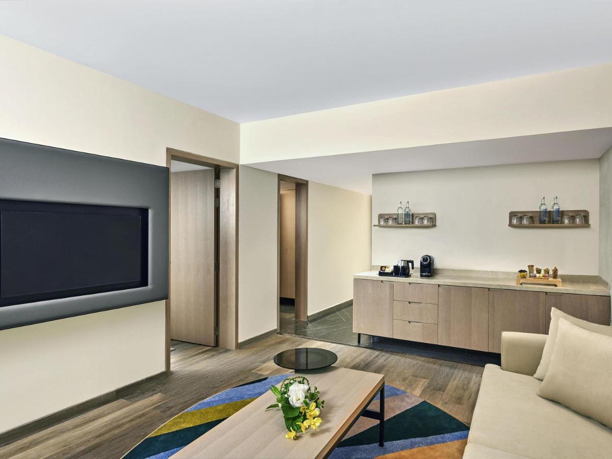 a living room with a couch and a tv at Novotel Mumbai International Airport in Mumbai