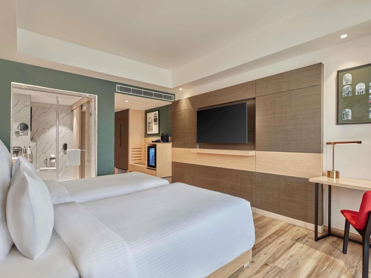 a bedroom with a white bed and a television at Novotel Jaipur Convention Centre in Jaipur