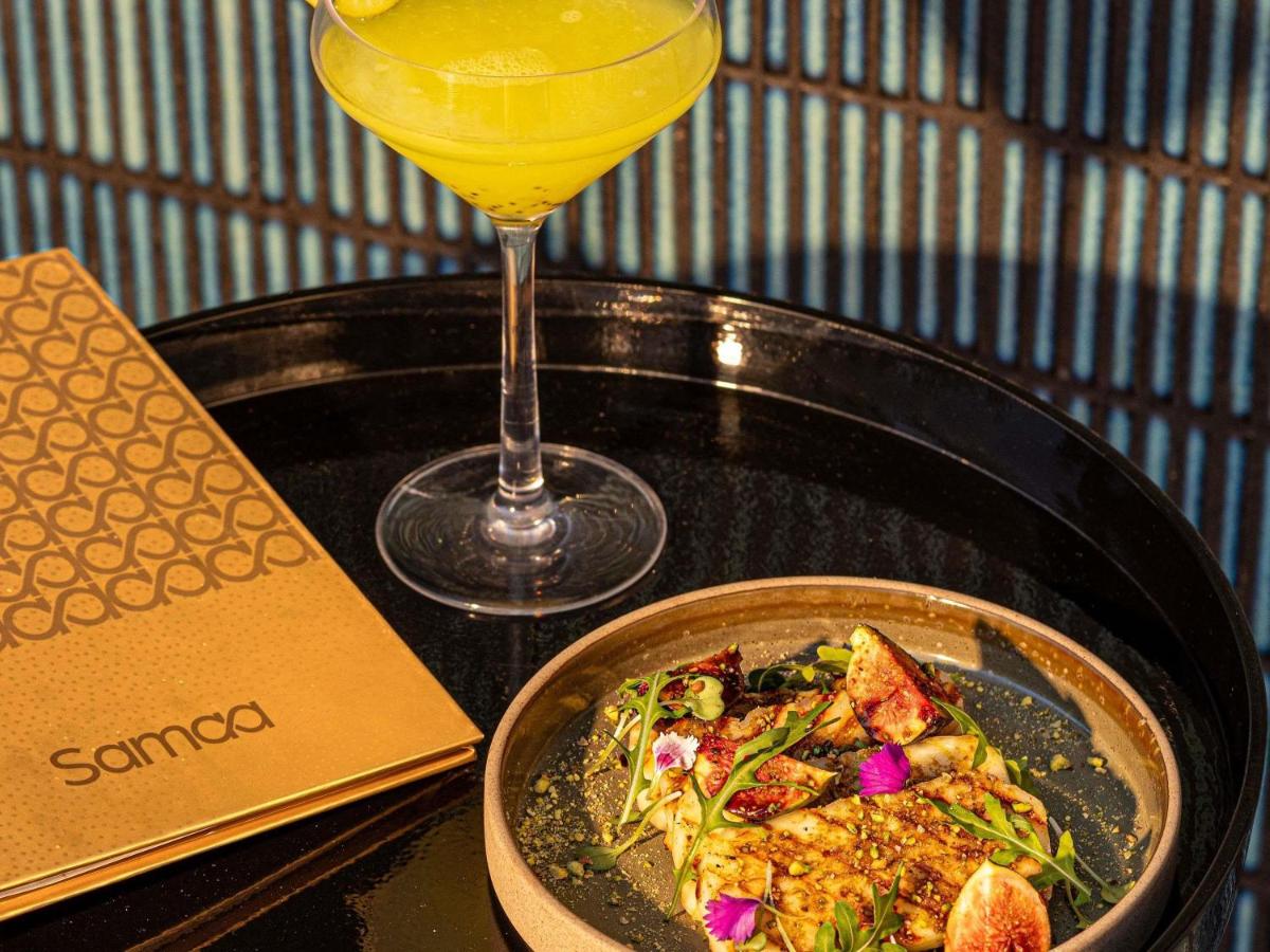 a table with a plate of food and a drink at Fairmont Mumbai in Mumbai