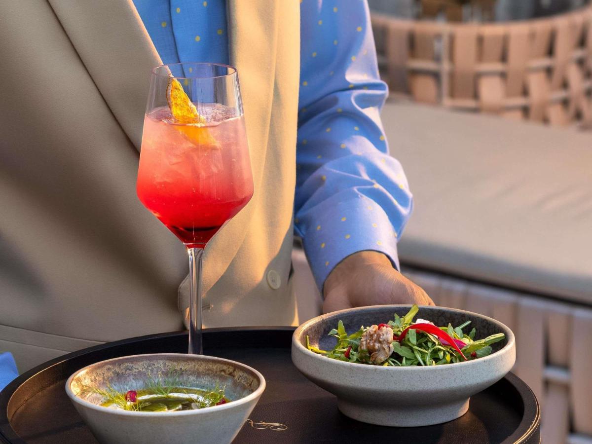 a person sitting at a table with a drink and salad at Fairmont Mumbai in Mumbai