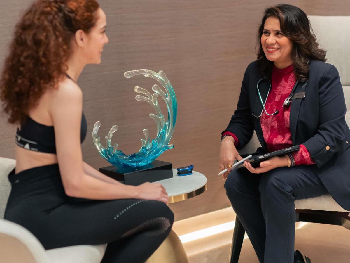 a woman talking to a woman sitting in a chair at Fairmont Mumbai in Mumbai