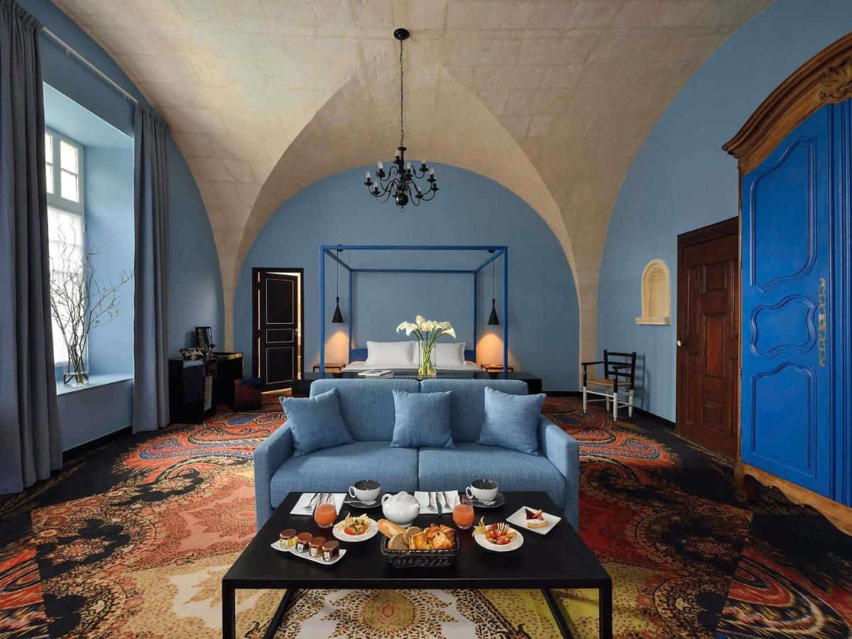 un salon avec un canapé bleu et une table avec de la nourriture dessus dans l'établissement Jules César Hotel & Spa Arles - MGallery Collection, à Arles