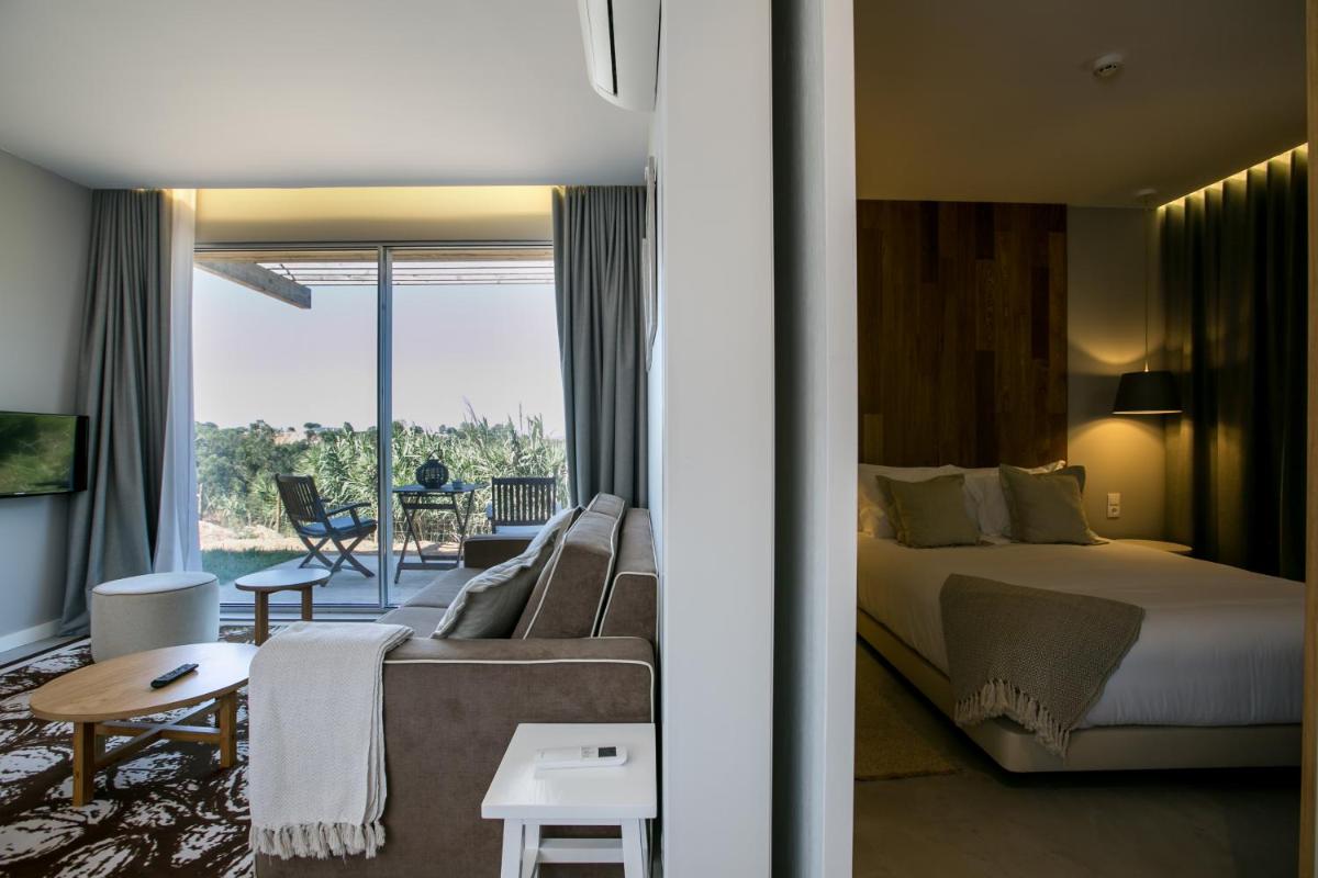 um quarto de hotel com uma cama e uma sala de estar em Vale d'Azenha Hotel Rural & Residences em Alcobaça
