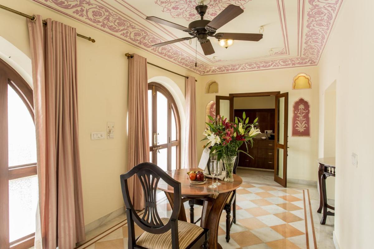 a dining room with a ceiling fan and a table with flowers at Royal Heritage Haveli - By Leisure Hotels in Jaipur