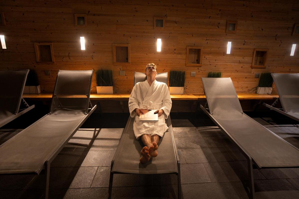 un homme assis sur un banc dans une salle d'attente dans l'établissement Château Hôtel, Restaurant & Spa De La Commanderie, à Eybens