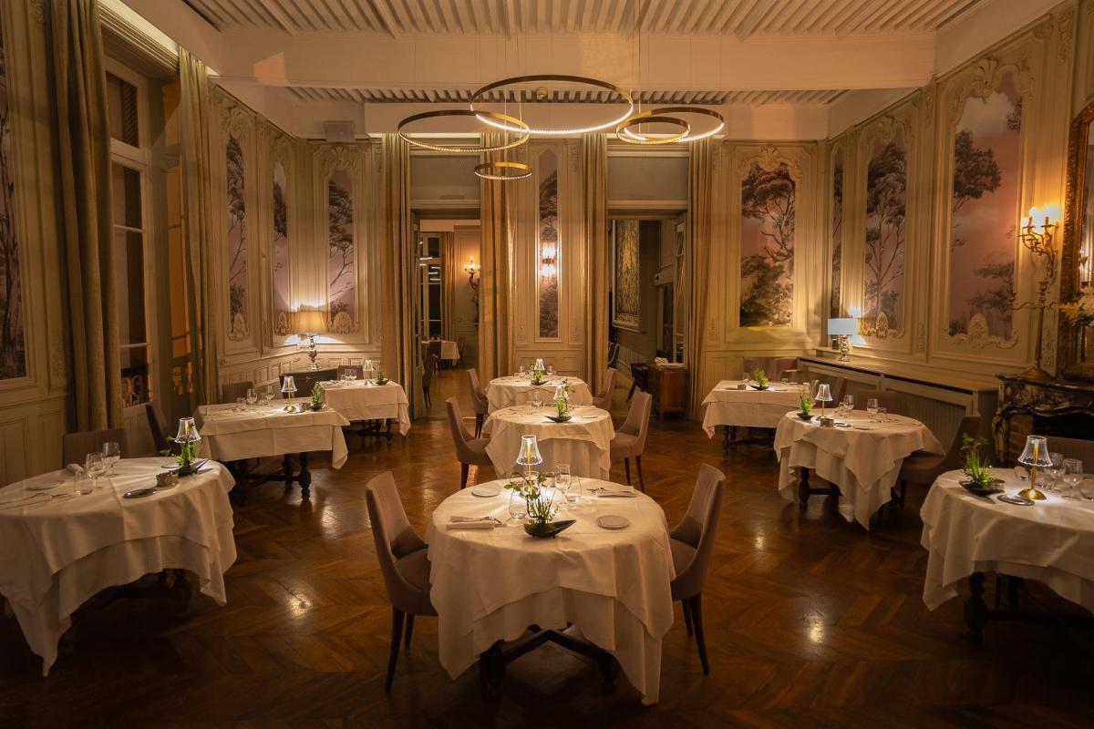 une salle à manger avec des tables recouvertes de nappes blanches dans l'établissement Château Hôtel, Restaurant & Spa De La Commanderie, à Eybens