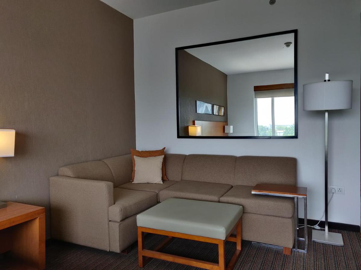 a living room with a couch and a mirror at Hyatt Place Gurgaon Udyog Vihar in Gurgaon