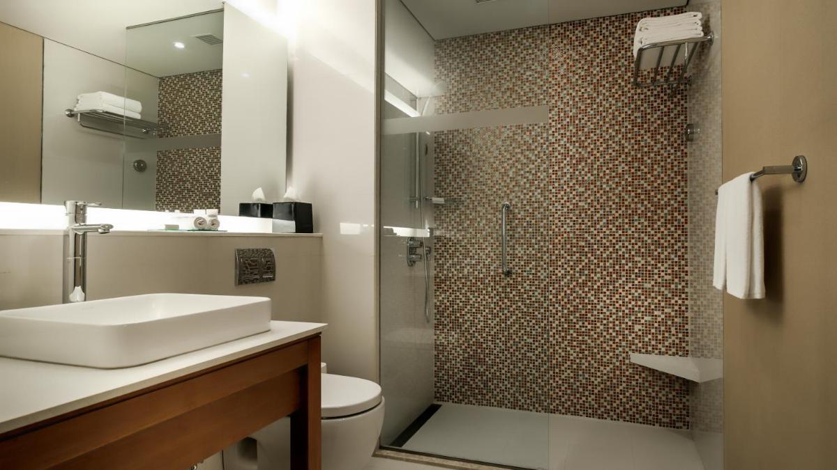 a bathroom with a toilet and a sink and a shower at Hyatt Place Gurgaon Udyog Vihar in Gurgaon
