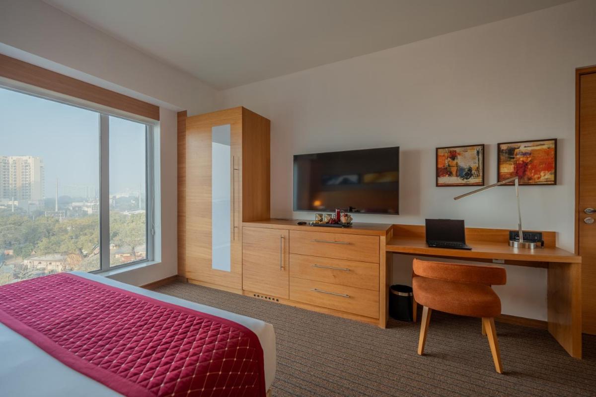 a bedroom with a bed and a desk with a television at Hyatt Place Gurgaon Udyog Vihar in Gurgaon