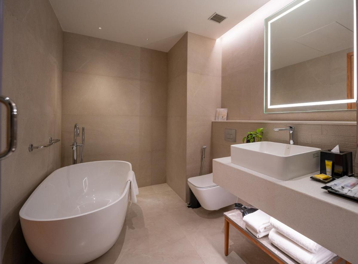a bathroom with a tub and a sink and a toilet at Hyatt Place Gurgaon Udyog Vihar in Gurgaon a bathroom with a tub and a sink and a toilet at Hyatt Place Gurgaon Udyog Vihar in Gurgaon