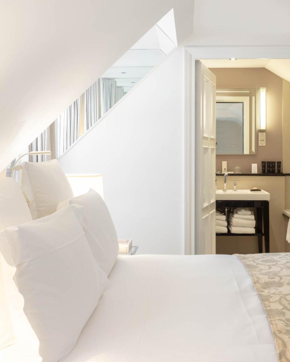 un lit blanc avec des oreillers blancs dans une chambre dans l'établissement Le Burgundy Paris, à Paris