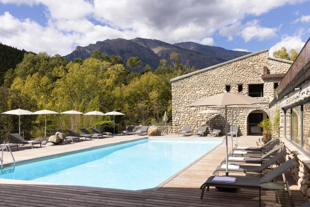 une piscine avec chaises longues et parasols à côté d'un bâtiment dans l'établissement Hotel E Caselle - Demeures & Châteaux, à Venaco