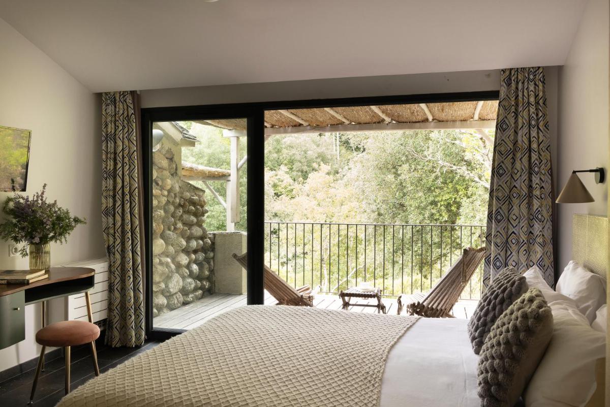 une chambre avec un grand lit et un balcon dans l'établissement Hotel E Caselle - Demeures & Châteaux, à Venaco