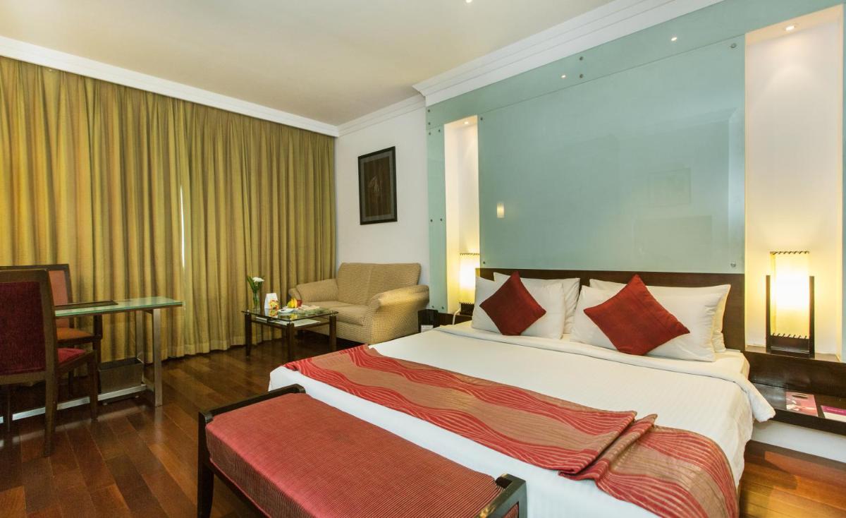 a hotel room with a large bed and a chair at The Chancery Pavilion in Bengaluru