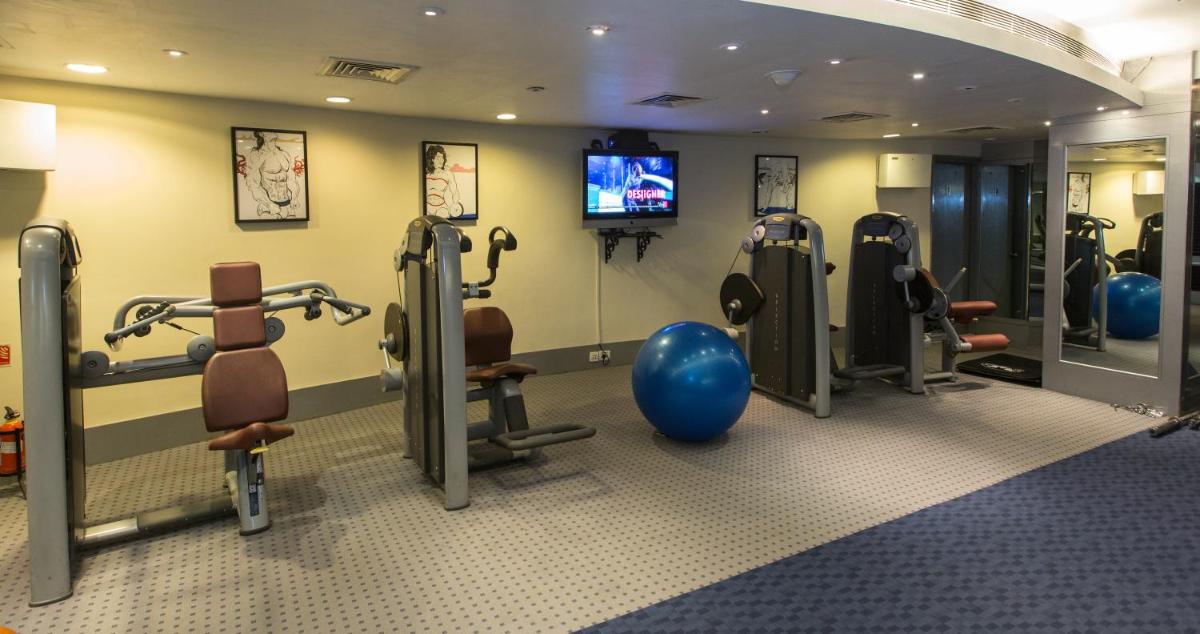 a gym with cardio equipment and a television in a room at The Chancery Pavilion in Bengaluru