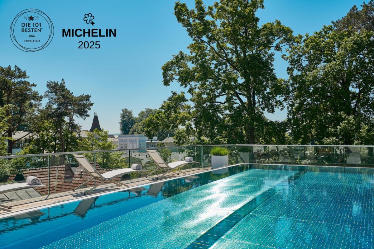 ein Swimmingpool auf dem Dach eines Gebäudes mit Stühlen in der Unterkunft ROEWERS Privathotel & Spa in Ostseebad Sellin