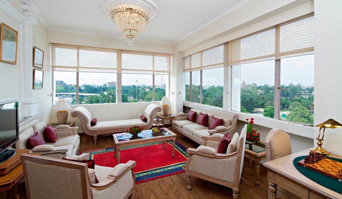 a living room with a couch and chairs and windows at Clarks Avadh in Lucknow