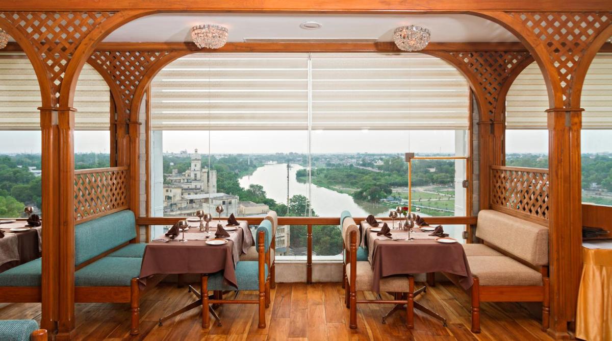 a restaurant with tables and chairs and a large window at Clarks Avadh in Lucknow