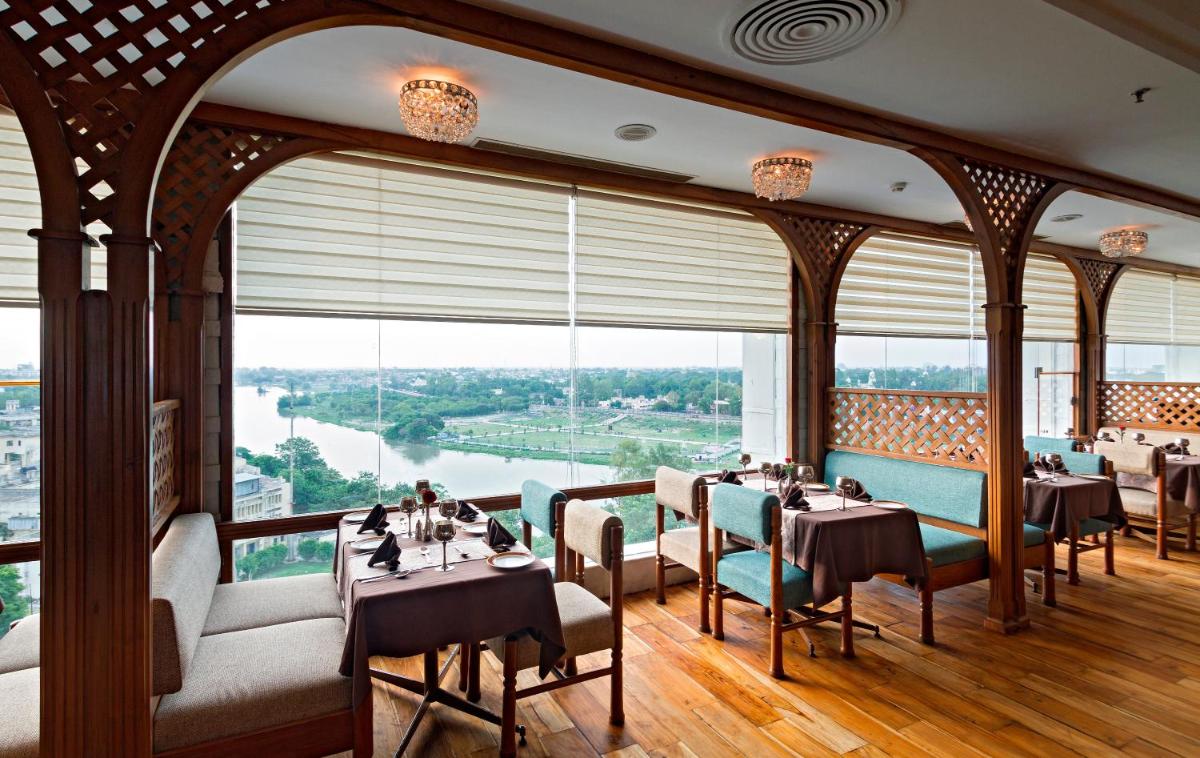 a dining room with tables and chairs and a large window at Clarks Avadh in Lucknow
