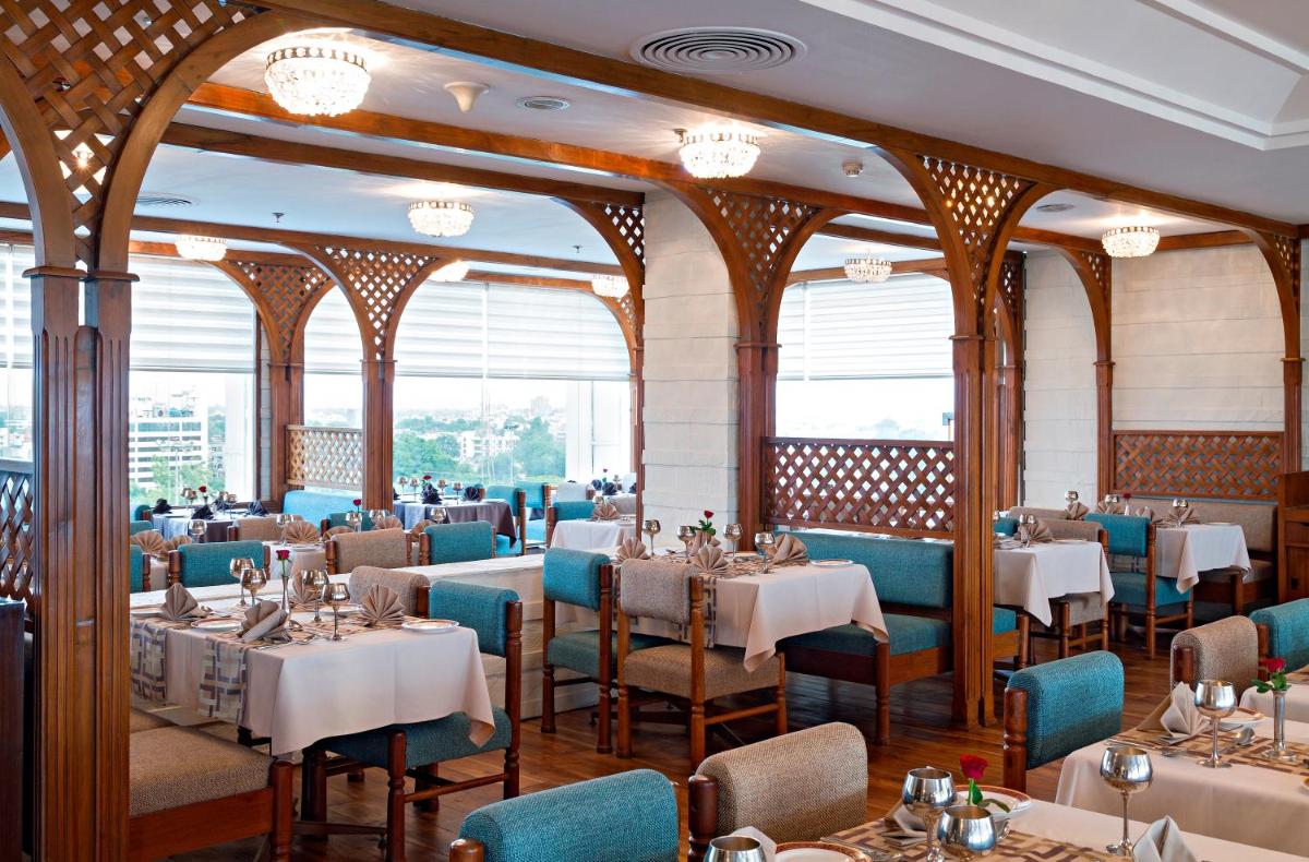 a restaurant with tables and chairs in a room at Clarks Avadh in Lucknow