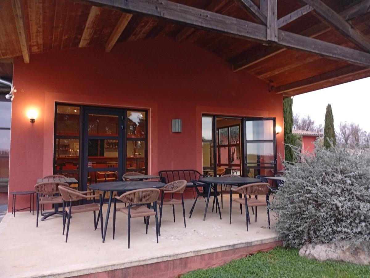 une terrasse avec des tables et des chaises devant un bâtiment dans l'établissement Domaine d'Agrippa Valence, à Châteauneuf-sur-Isère