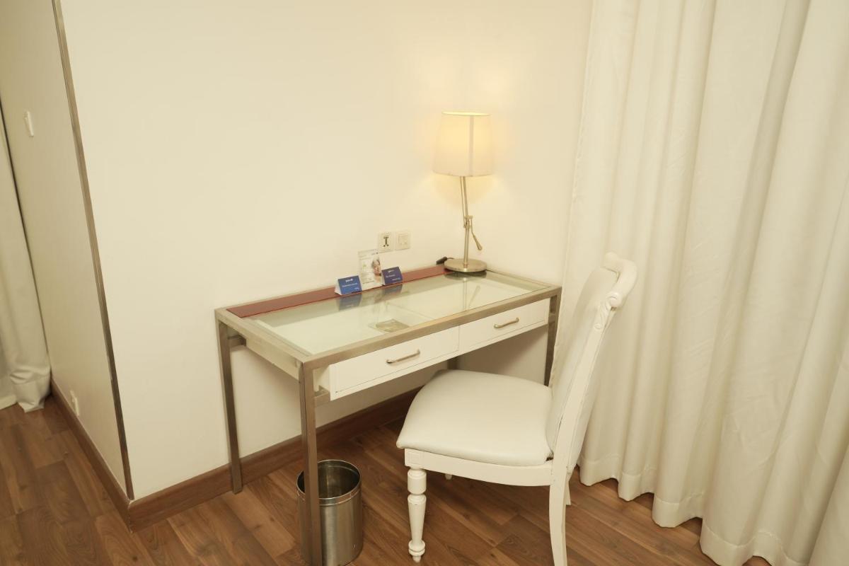 a desk with a lamp and a chair in a room at Radisson Blu Kochi in Cochin