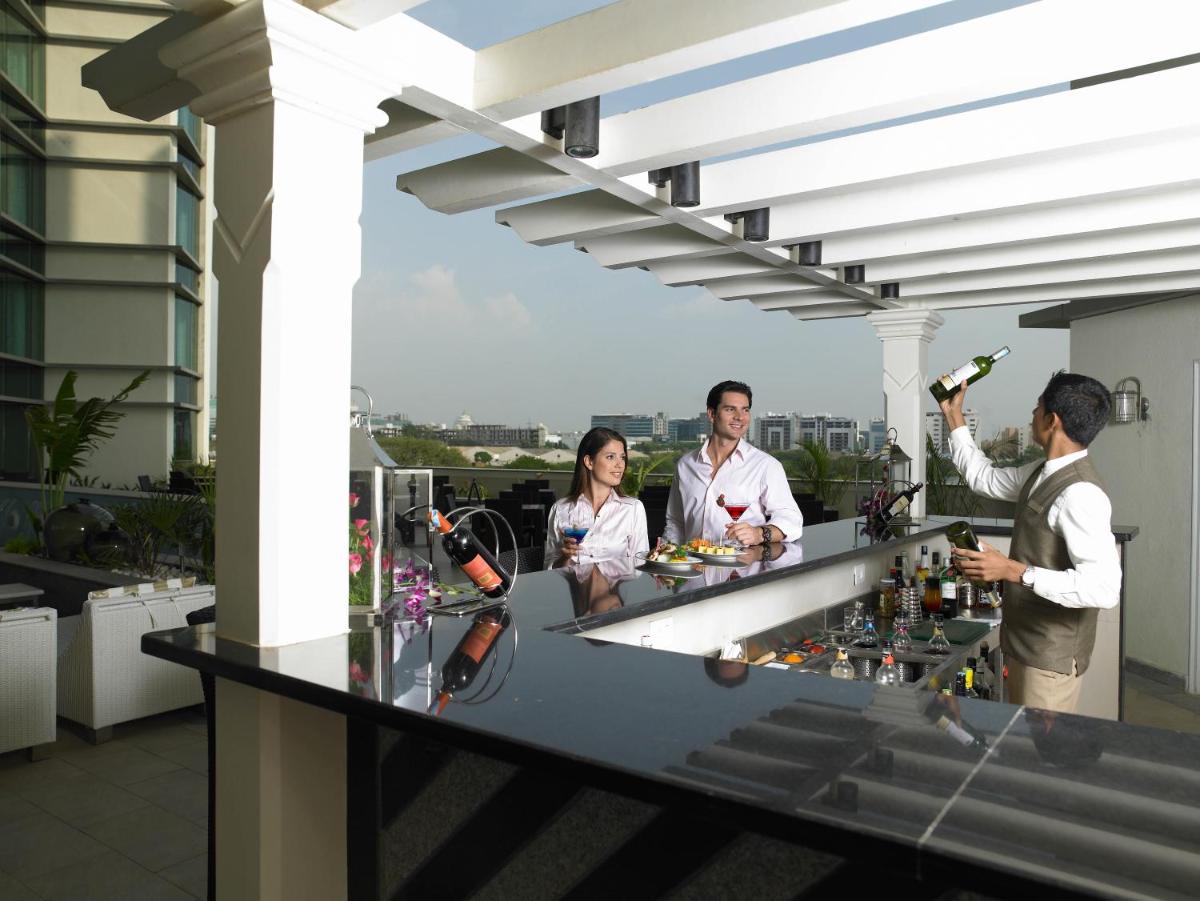 a group of people standing at a bar on a rooftop at The Zuri Whitefield Bengaluru in Bengaluru